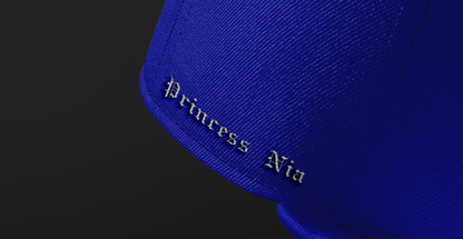 Side view of the Princess Nia Snapback, showcasing the embroidered text 'Princess Nia' in elegant black lettering on the royal blue fabric.